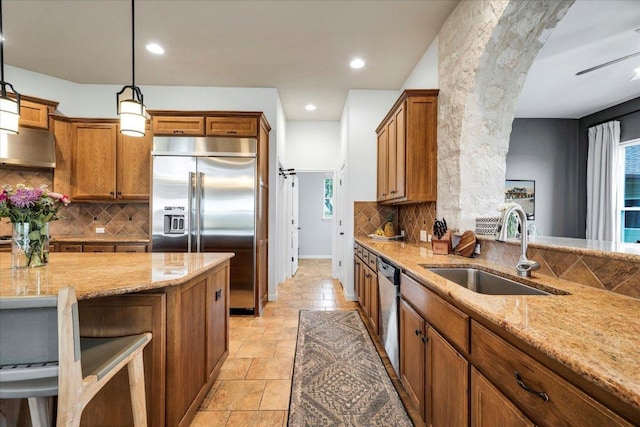 440 Currie Ranch Rd, Wimberley, TX 78676 - kitchen with light stone counters, a sink, appliances with stainless steel finishes, and brown cabinetry