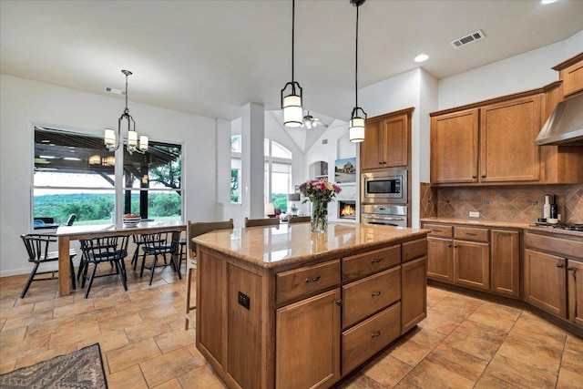 440 Currie Ranch Rd, Wimberley, TX 78676 - kitchen with stainless steel appliances, a kitchen island, brown cabinets, backsplash, and visible vents