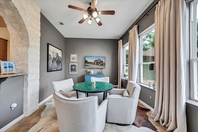 440 Currie Ranch Rd, Wimberley, TX 78676 - dining area with arched walkways, stone finish flooring, baseboards, visible vents, and a ceiling fan