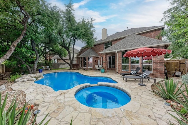 view of swimming pool with a pool with connected hot tub, a fenced backyard, and a patio area