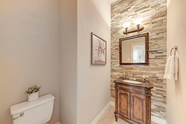 half bath featuring toilet, tile patterned floors, vanity, and baseboards