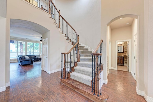 2402 Silent Brook Trl, Round Rock, TX 78665 - staircase with wood-type flooring, ceiling fan, arched walkways, and a high ceiling
