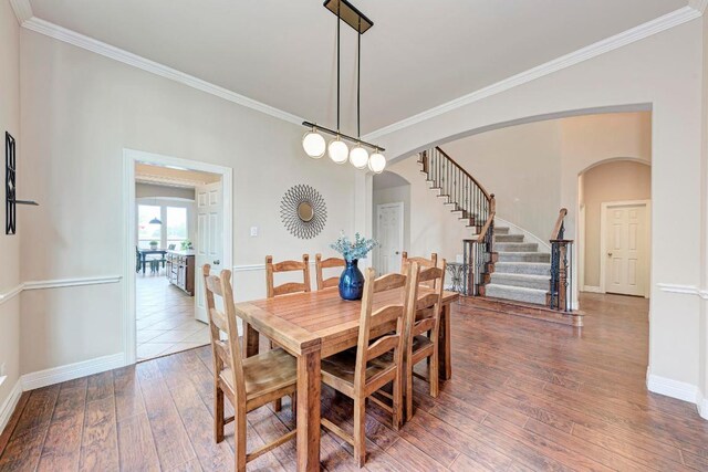 2402 Silent Brook Trl, Round Rock, TX 78665 - dining room with arched walkways, wood-type flooring, stairs, and crown molding