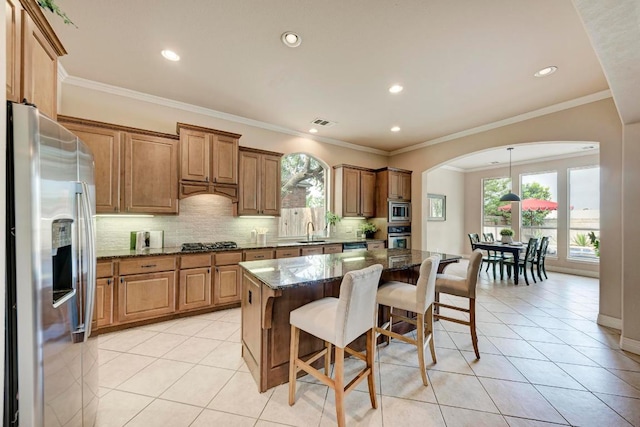 2402 Silent Brook Trl, Round Rock, TX 78665 - kitchen featuring stainless steel appliances, light tile patterned flooring, dark stone countertops, a breakfast bar, and arched walkways