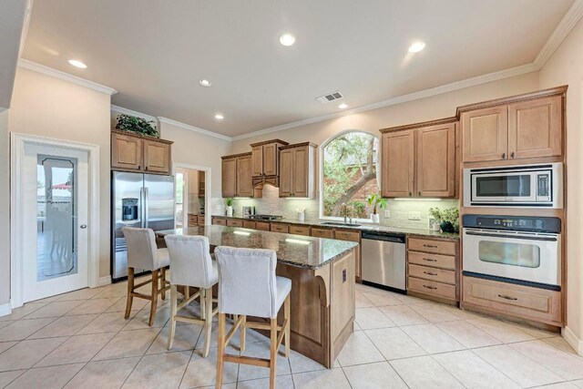2402 Silent Brook Trl, Round Rock, TX 78665 - kitchen with stainless steel appliances, a kitchen island, a breakfast bar, dark stone countertops, and backsplash