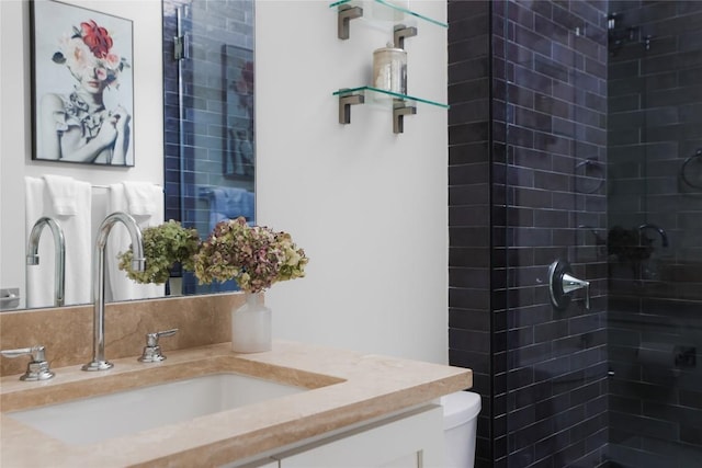bathroom featuring toilet, a tile shower, and vanity
