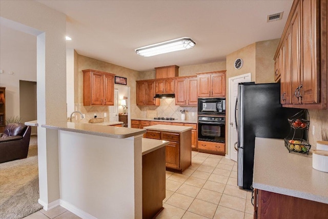 15617 Pumpkin Ridge Dr, Austin, TX 78717 - kitchen with black appliances, a peninsula, light countertops, tasteful backsplash, and under cabinet range hood