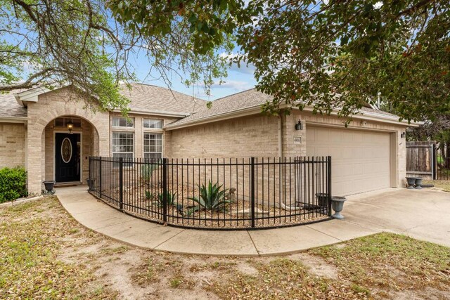 4906 Thunderbird Dr, Lago Vista, TX 78645 - view of front facade with an attached garage, driveway, brick siding, and a shingled roof