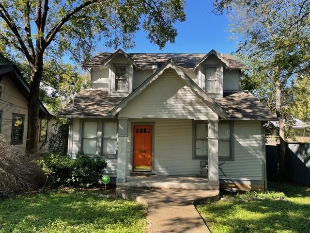 traditional-style home featuring a porch and a front lawn