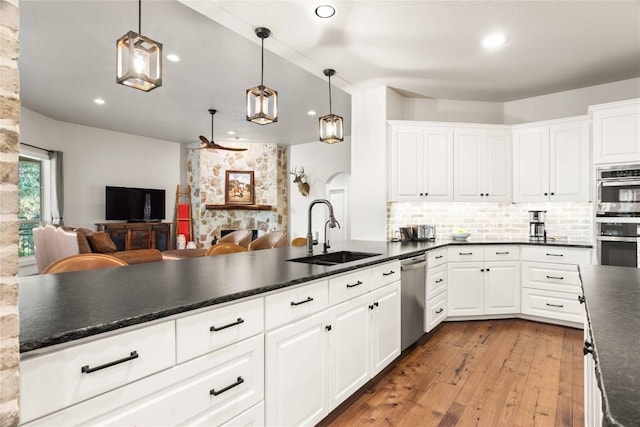 kitchen featuring hardwood / wood-style flooring, white cabinets, a sink, appliances with stainless steel finishes, and open floor plan