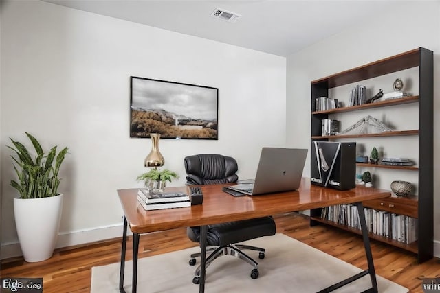 office area featuring wood finished floors, visible vents, and baseboards