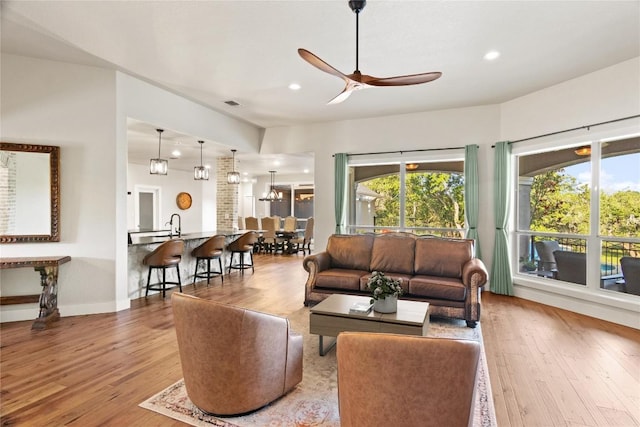 living area with a ceiling fan, visible vents, wood finished floors, and plenty of natural light