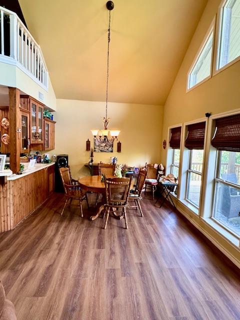 dining room featuring a chandelier, high vaulted ceiling, and dark wood-style flooring
