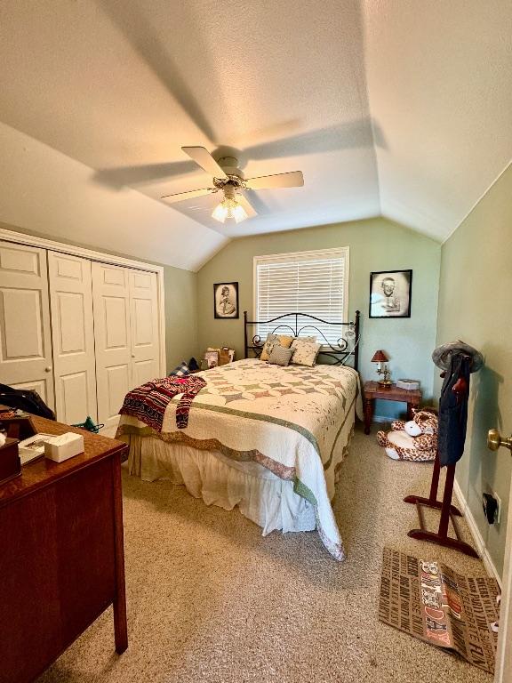 bedroom with ceiling fan, carpet floors, a closet, and lofted ceiling