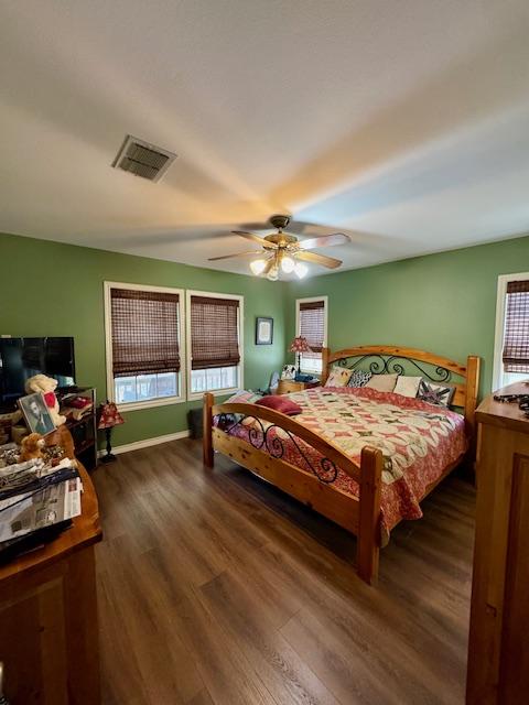 bedroom featuring visible vents, ceiling fan, multiple windows, and dark wood-type flooring