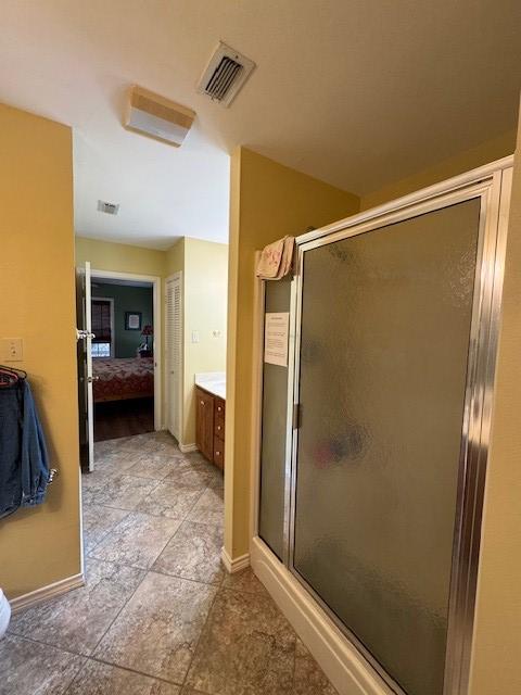ensuite bathroom with visible vents, connected bathroom, a shower stall, and vanity