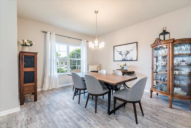 dining room featuring baseboards, an inviting chandelier, and light wood-style flooring