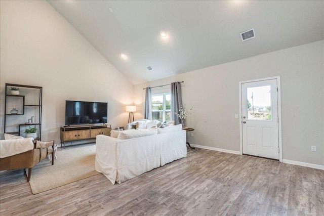 living area featuring visible vents, wood finished floors, baseboards, and high vaulted ceiling
