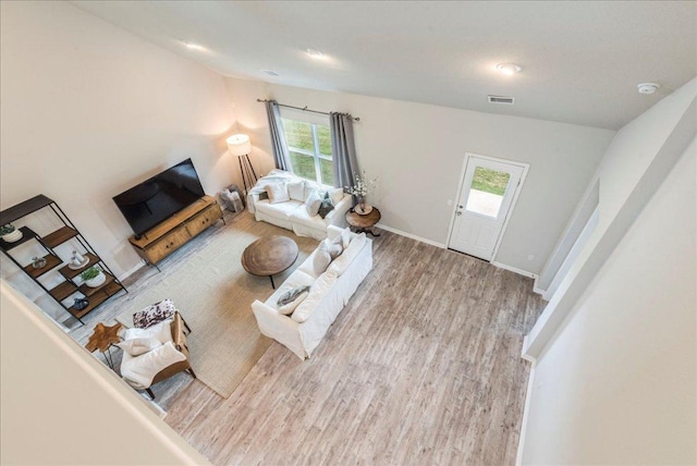 living room with vaulted ceiling, visible vents, plenty of natural light, and wood finished floors