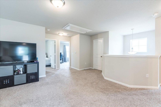 unfurnished living room featuring attic access, baseboards, and carpet
