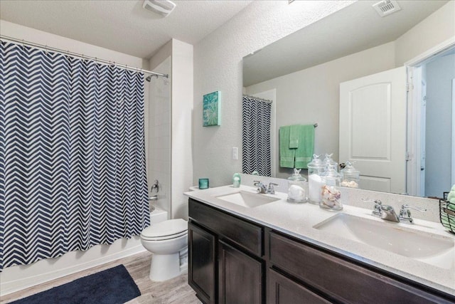 full bathroom with toilet, visible vents, wood finished floors, and a sink