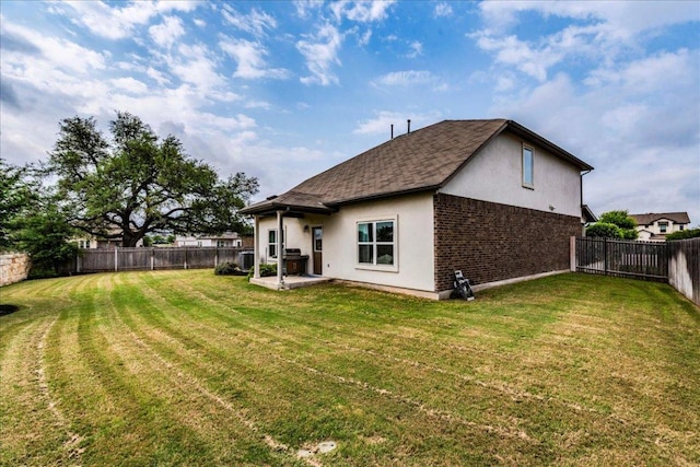 rear view of house featuring a yard, stucco siding, a fenced backyard, and a patio