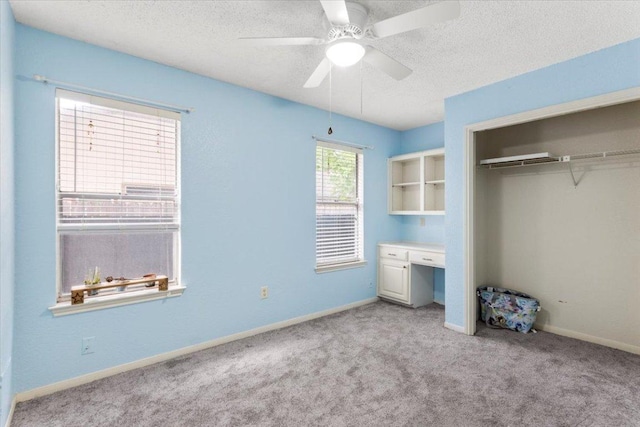 unfurnished bedroom with a textured ceiling, a ceiling fan, carpet flooring, and a closet