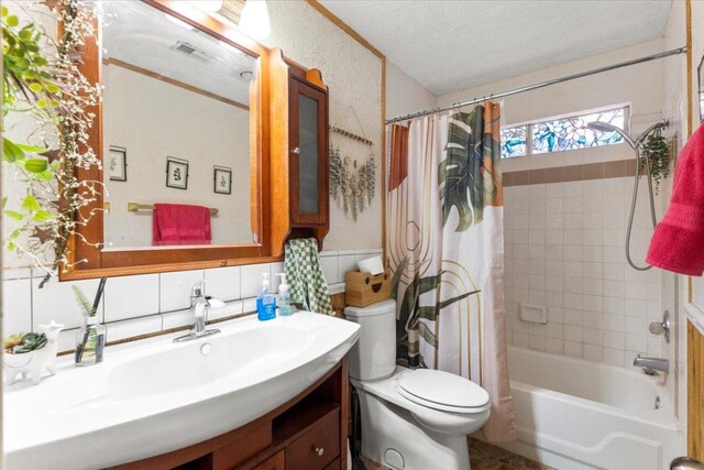 full bathroom with toilet, vanity, visible vents, shower / tub combo with curtain, and a textured ceiling