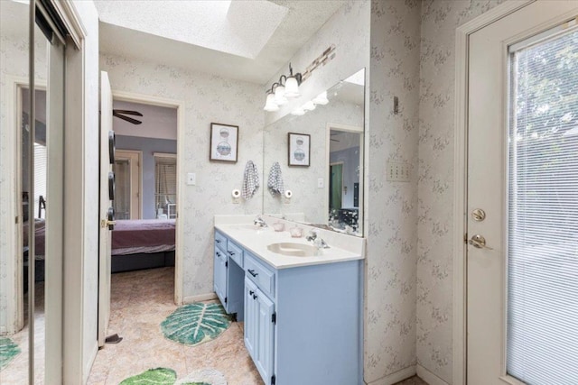 bathroom with double vanity, a textured ceiling, connected bathroom, and a sink