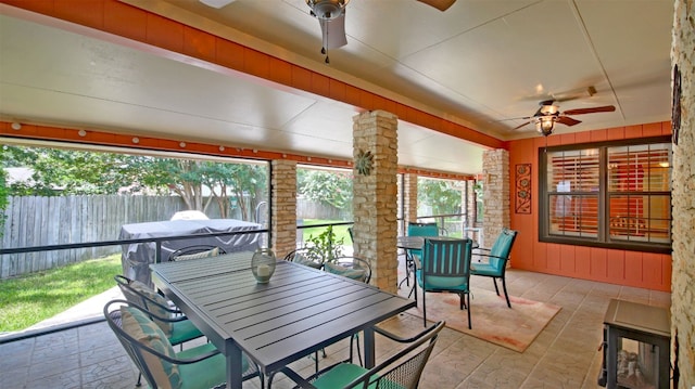 sunroom featuring a ceiling fan, outdoor dining space, and plenty of natural light