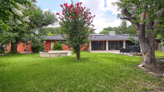back of house featuring a chimney, a yard, a sunroom, roof with shingles, and a patio area