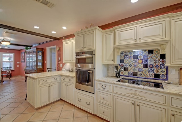 kitchen featuring cream cabinetry, visible vents, a peninsula, and black electric stovetop