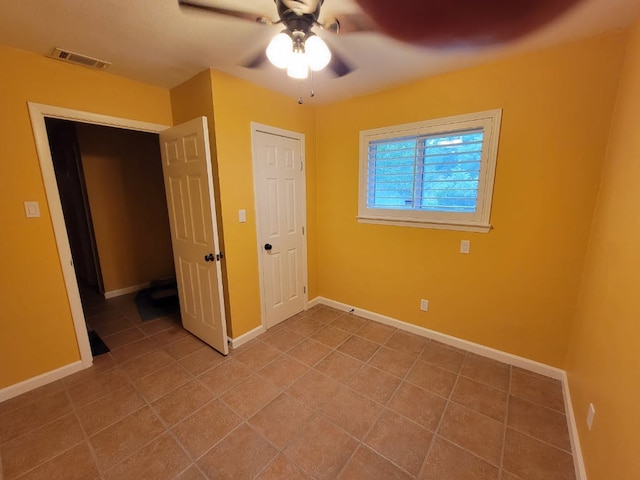 unfurnished bedroom featuring baseboards, visible vents, tile patterned floors, and ceiling fan