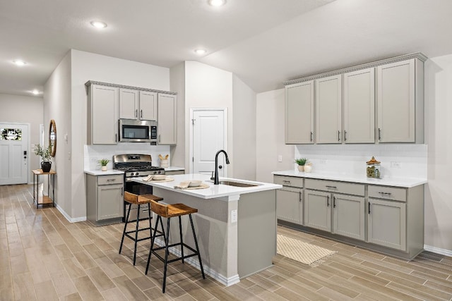 135 Hackberry Ln, Bastrop, TX 78602 - kitchen with gray cabinets, appliances with stainless steel finishes, a sink, light wood-type flooring, and vaulted ceiling