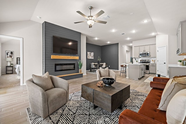 135 Hackberry Ln, Bastrop, TX 78602 - living room with lofted ceiling, ceiling fan, light wood-style floors, a large fireplace, and baseboards