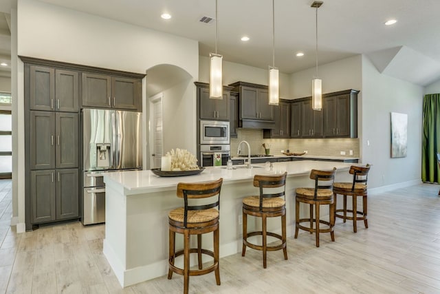 2724 Rain Song Dr, Leander, TX 78641 - kitchen with stainless steel appliances, light wood finished floors, tasteful backsplash, light countertops, and a large island with sink