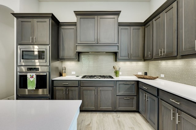 2724 Rain Song Dr, Leander, TX 78641 - kitchen featuring appliances with stainless steel finishes, light countertops, decorative backsplash, and under cabinet range hood