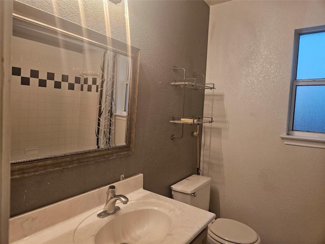 bathroom with curtained shower, a textured wall, toilet, and vanity