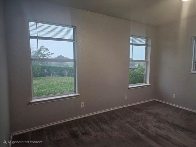 empty room with baseboards and dark colored carpet