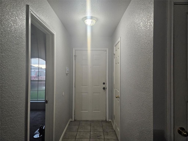 doorway featuring tile patterned flooring and a textured wall