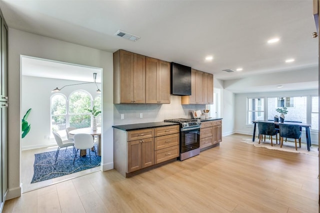 kitchen with gas stove, dark countertops, visible vents, and light wood-style flooring
