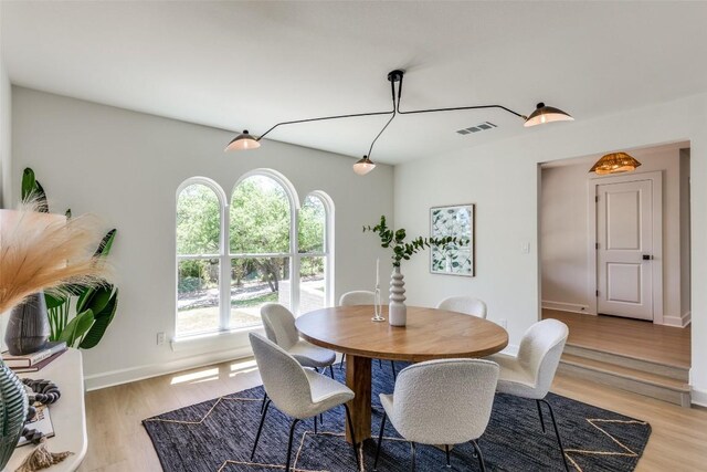dining space featuring visible vents, light wood-style flooring, and baseboards
