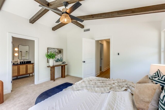 bedroom featuring a sink, visible vents, baseboards, light carpet, and vaulted ceiling with beams