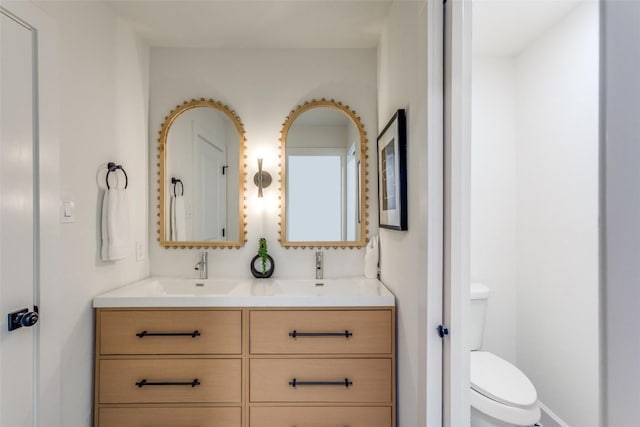 bathroom featuring toilet, double vanity, and a sink