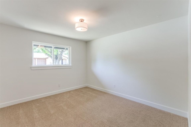 unfurnished room with baseboards and light colored carpet