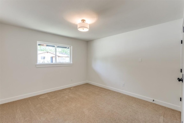 unfurnished room featuring baseboards and light carpet