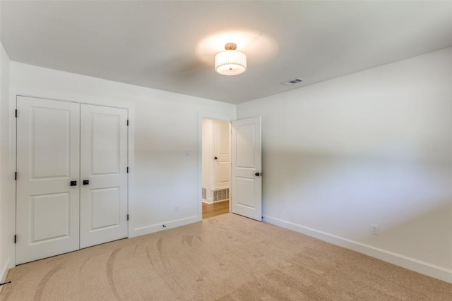 unfurnished bedroom with carpet flooring, a closet, visible vents, and baseboards