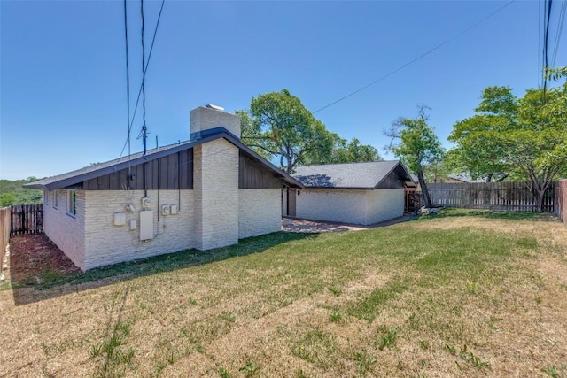 back of house with a lawn, a chimney, board and batten siding, and a fenced backyard