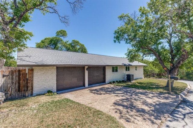 ranch-style house with fence, driveway, a front lawn, cooling unit, and an attached garage