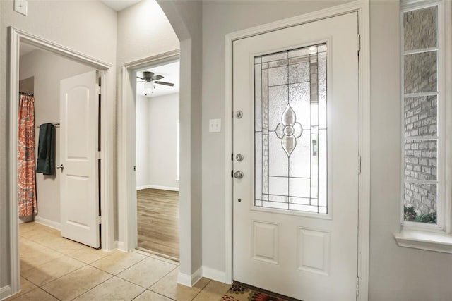 foyer entrance featuring light tile patterned floors, baseboards, and arched walkways